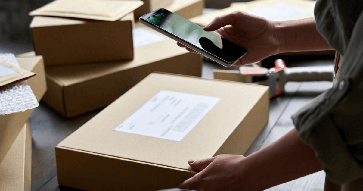 9Vendedora de almacén escanea el código de barras de paquetes de su mobile commerce.